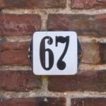 A close-up of a house number plate reading “67” on a brick wall. Image for the What Does 67 Even Mean ESL lesson from betterclass, exploring viral internet trends, online humor, and digital culture through discussion and vocabulary activities.