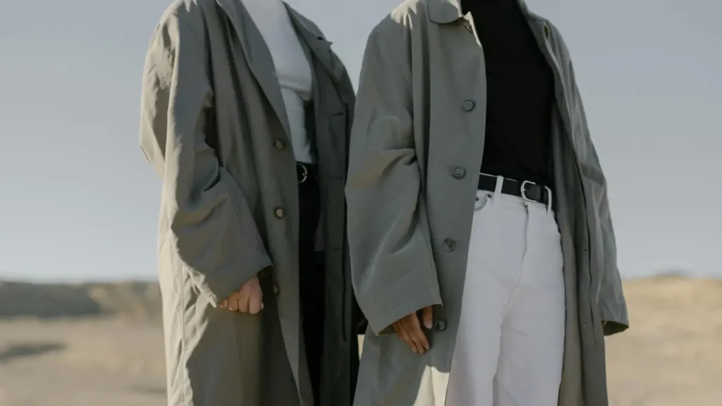 Two people wearing long, trench-style coats inspired by military outerwear, illustrating how modern fashion still reflects clothing originally designed for soldiers.