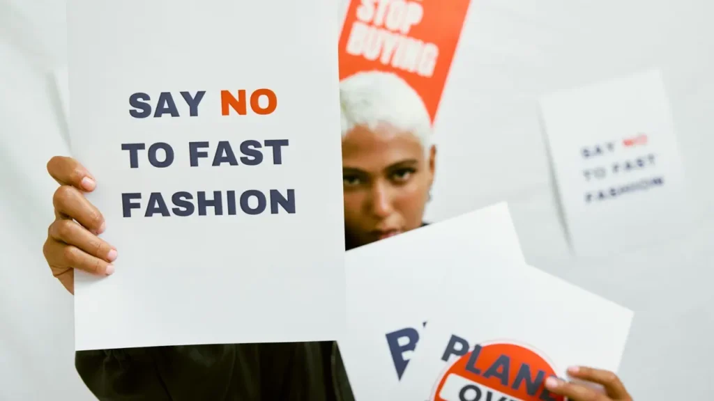Protesters holding signs against fast fashion during a demonstration in Paris, including messages like “Say No to Fast Fashion.” Image for a B2 ESL lesson on environmental issues, consumerism, and social activism from betterclass.