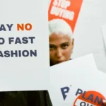 Protesters holding signs against fast fashion during a demonstration in Paris, including messages like “Say No to Fast Fashion.” Image for a B2 ESL lesson on environmental issues, consumerism, and social activism from betterclass.