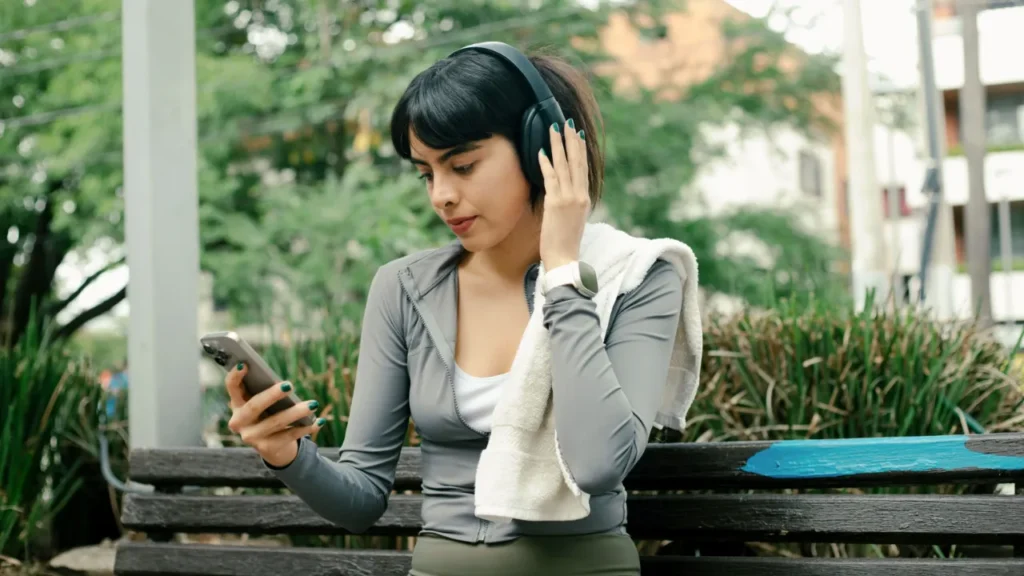 Woman with headphones relaxing on park bench illustrating mindful lifestyle choices and resisting consumer pressure from social media