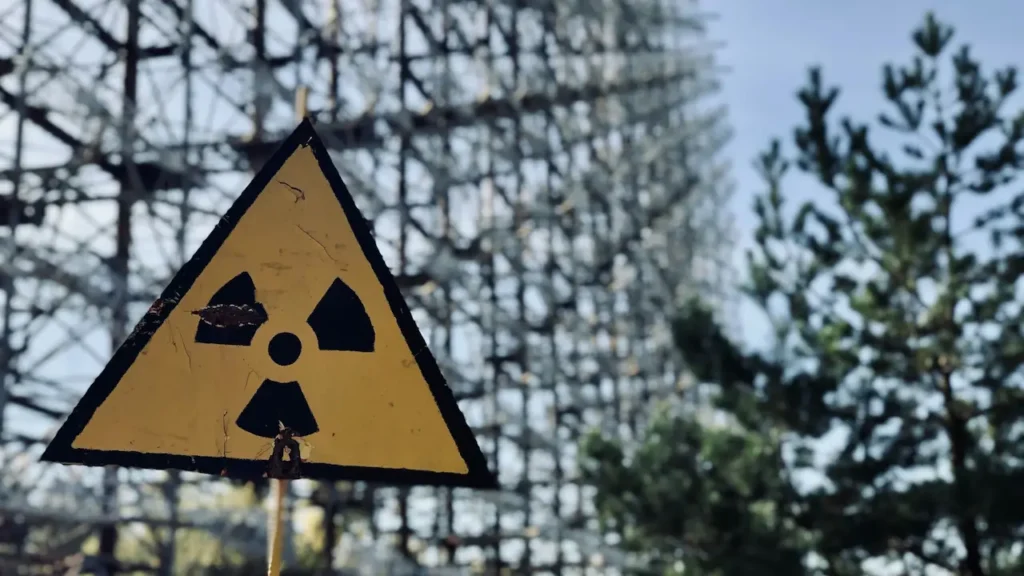 Weathered radiation warning sign at Chernobyl with abandoned structure in background showing nuclear disaster exclusion zone