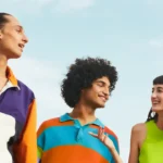 Three diverse young people smiling together outdoors, illustrating social connections in English articles for students.