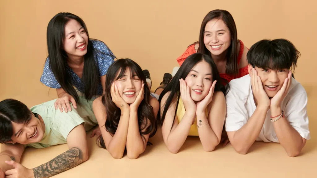 K-Culture & K-Beauty Young diverse group smiling while lying on beige background representing Korean beauty and skincare culture trends together