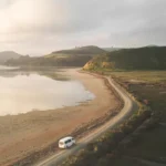 B1 English lesson plan featured image showing white van on scenic coastal road during golden hour for Road Trip to a New Life