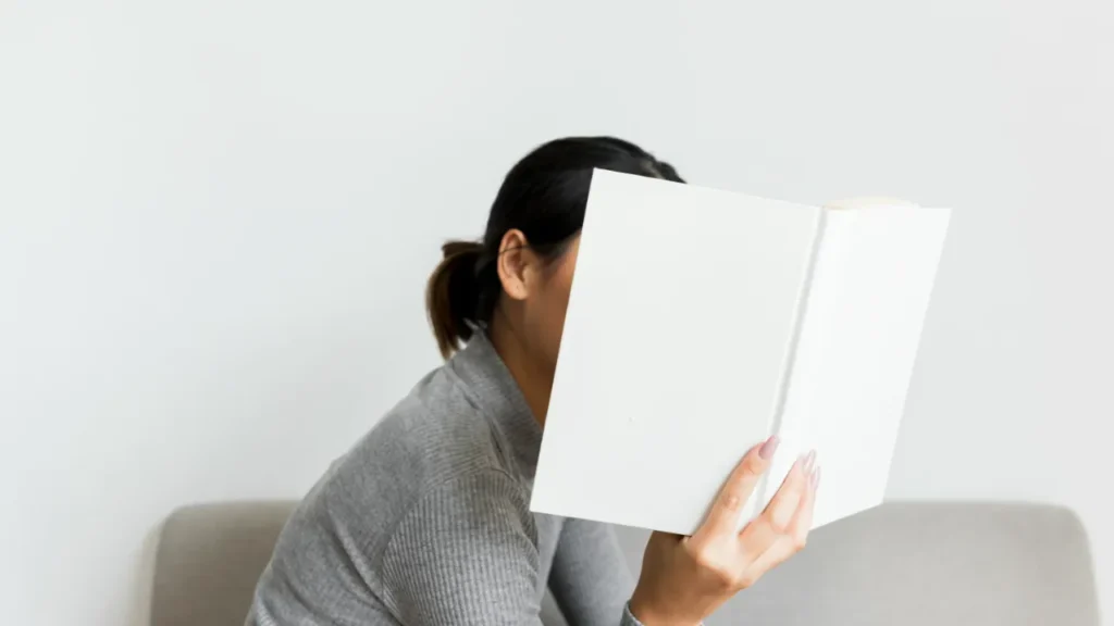 A woman hiding behind a book, representing the need to switch off from work in a B2 English lesson plan about work-life balance