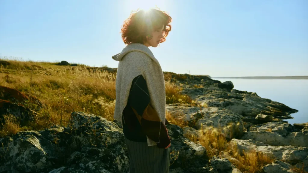 A person standing on a rocky coastline in golden sunlight — lesson plan thumbnail for a C1 English lesson on building habits.