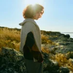 A person standing on a rocky coastline in golden sunlight — lesson plan thumbnail for a C1 English lesson on building habits.