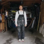 A man in paint-covered overalls stands in a garage in a still from the B1 ESL lesson plan "It Was Great Until It Wasn't."