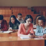 Students using smartphones in a university classroom, ignoring their studies — a scene the Dutch phone ban aims to change.