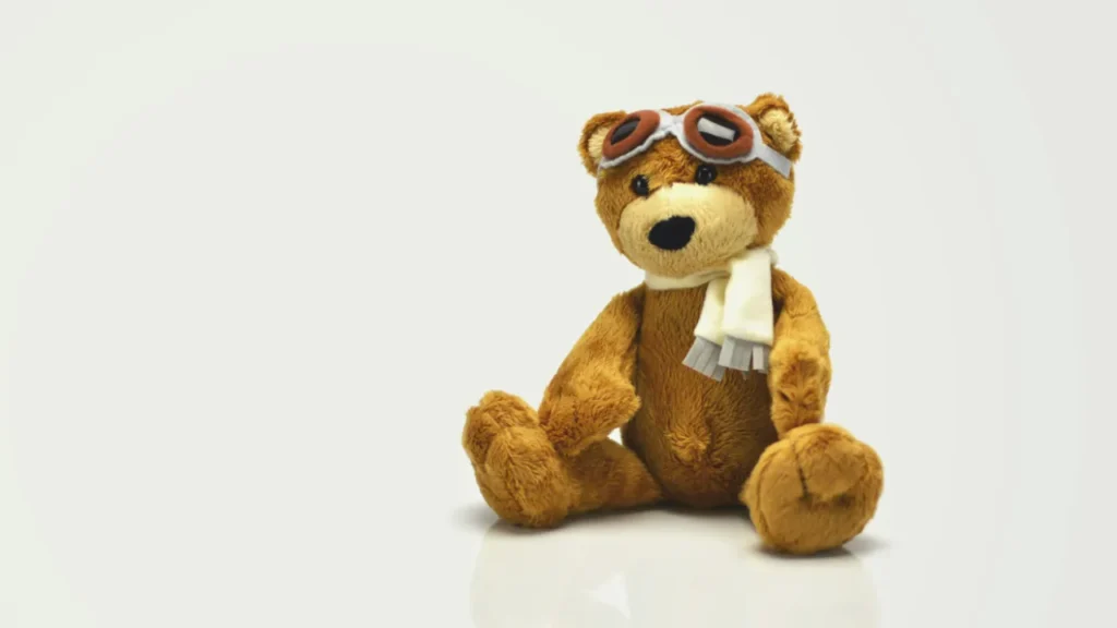 A brown teddy bear wearing pilot goggles and a white scarf, used in a B1 ESL lesson plan about toys and childhood.