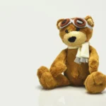 A brown teddy bear wearing pilot goggles and a white scarf, used in a B1 ESL lesson plan about toys and childhood.