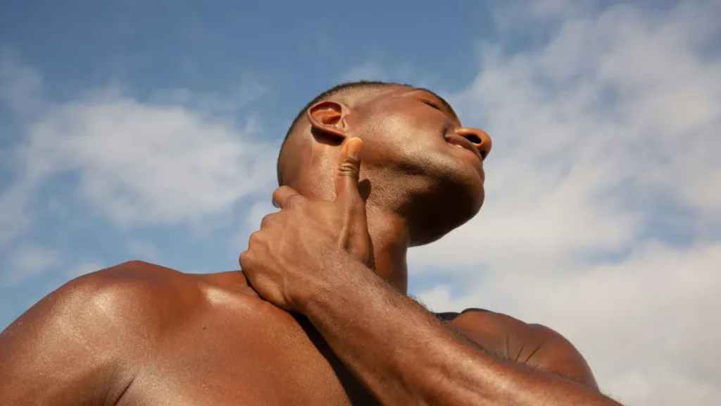 A man tilts his head back and touches his jawline, illustrating the looksmaxxing trend discussed in this ESL lesson.