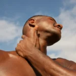 A man tilts his head back and touches his jawline, illustrating the looksmaxxing trend discussed in this ESL lesson.