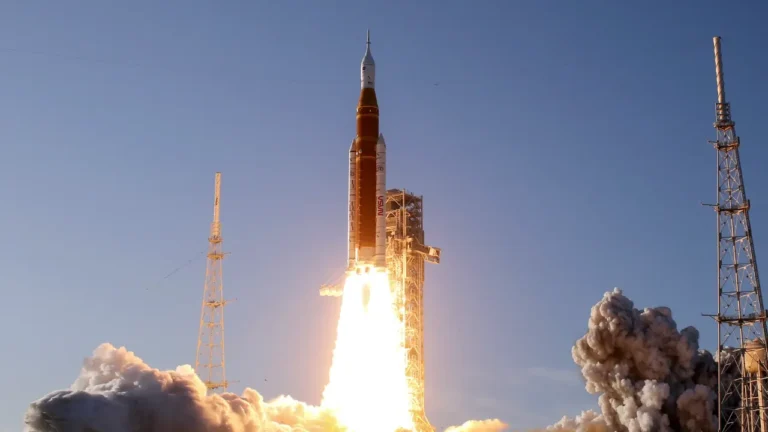 NASA Artemis rocket launches into blue sky, billowing smoke and flames at liftoff, space exploration lesson