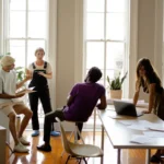 Small group of adults having a discussion in a bright room, perfect for a B1 storytelling lesson on personal narratives.